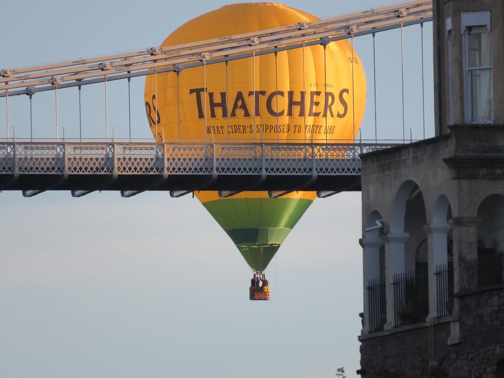 Hot air balloon floating past bridge