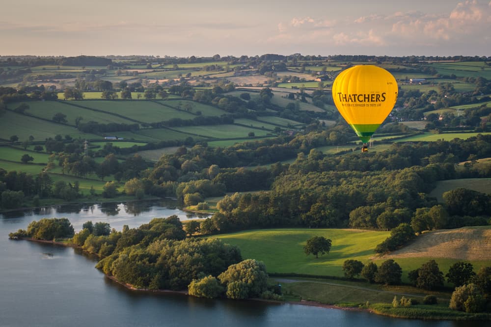 Hot air balloon flying over kent countryside and lake